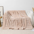 Thick square coral fleece blanket in a solid colour, draped over a sofa.