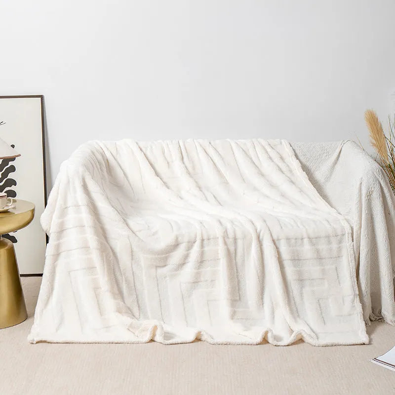 Thick square coral fleece blanket in a solid colour, draped over a sofa.