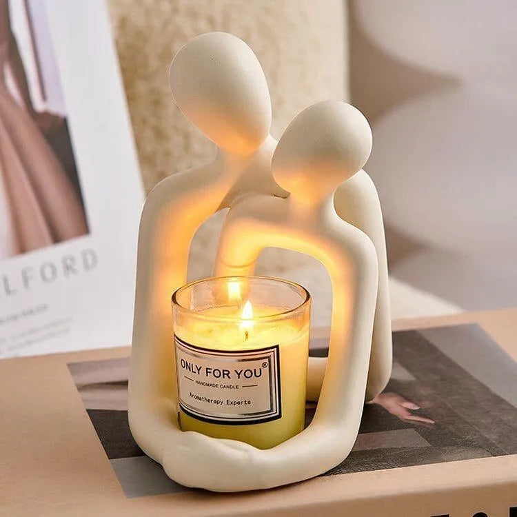 Modern style resin statue of a couple in milky white or gold colour on a wooden surface.