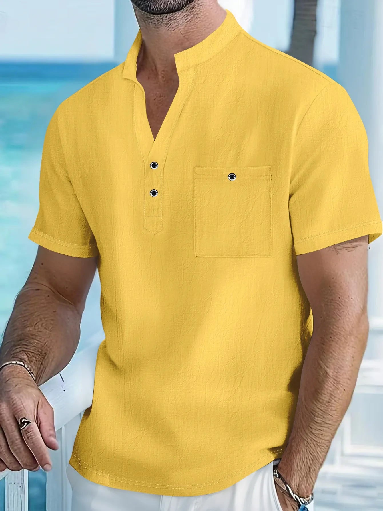 Man wearing a light-coloured, loose fit linen t-shirt with a stand collar and short sleeves.
