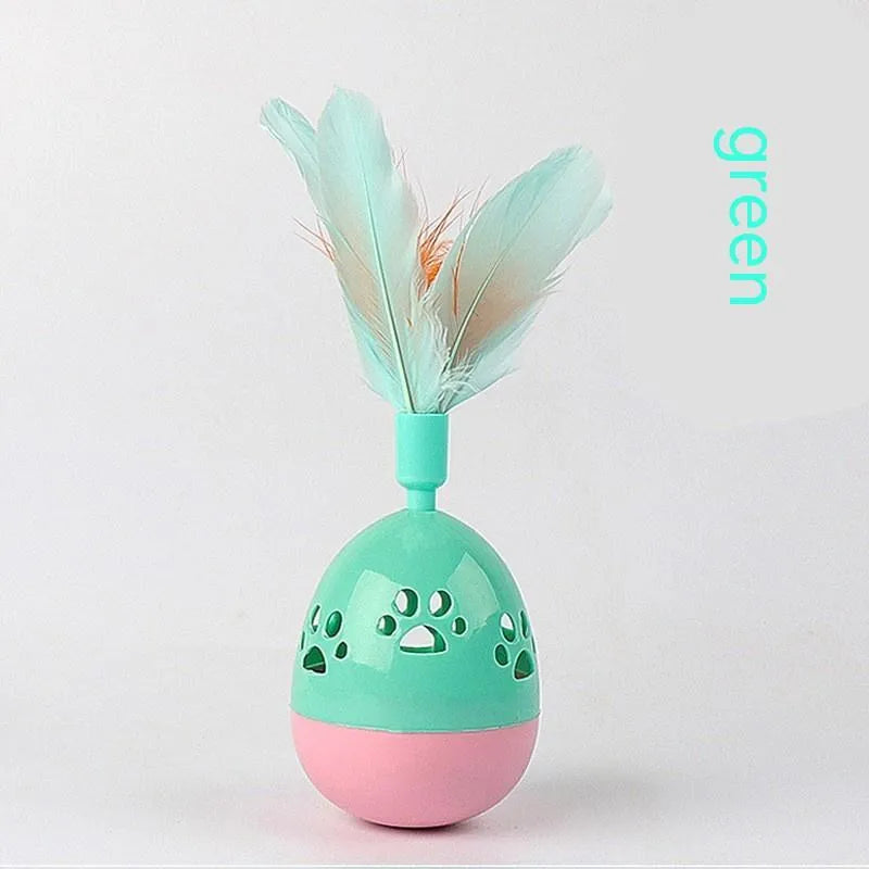 Green cat tumbler bell interactive toy with hollow footprints and feathers on a light floor