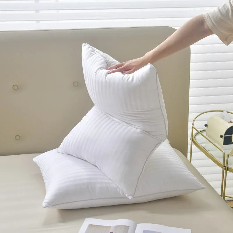 White cotton satin stripe pillow with feather and cotton filler on a bed.