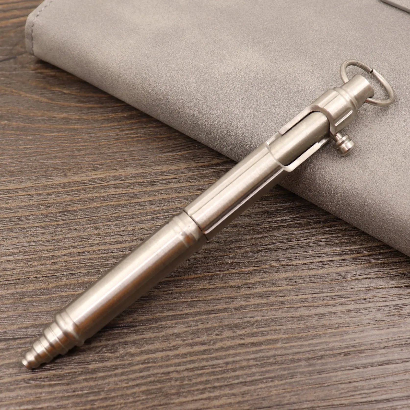 Close-up of a solid brass bolt action tactical pen with a press mechanism on a dark surface.