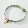 Green adjustable pet collar with a metal bell pendant and a matching bow tie on a white background.