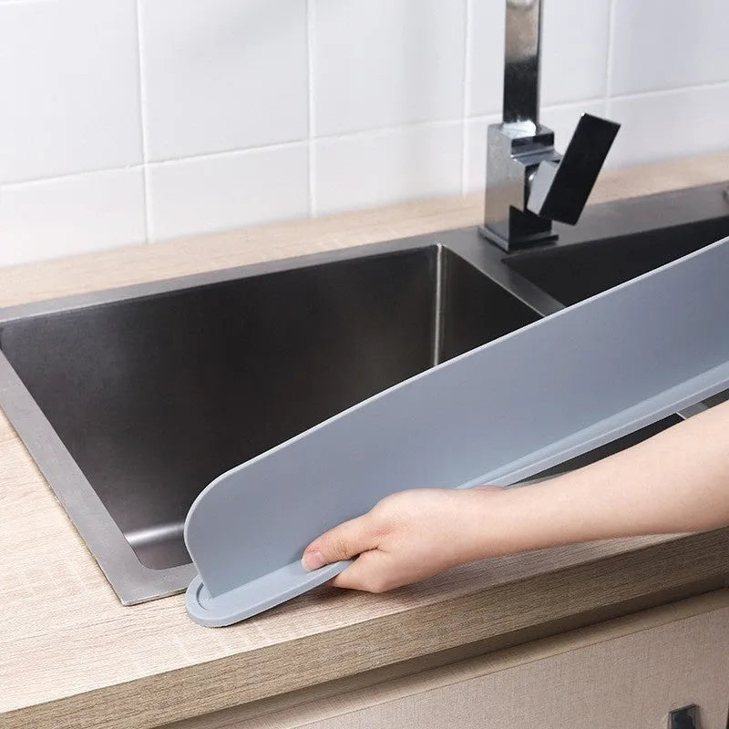 Grey silicone sink splash guard water blocking plate placed on a kitchen sink edge