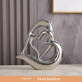 Modern white porcelain heart ornament in a metallic finish, showing its geometric shape on a table.