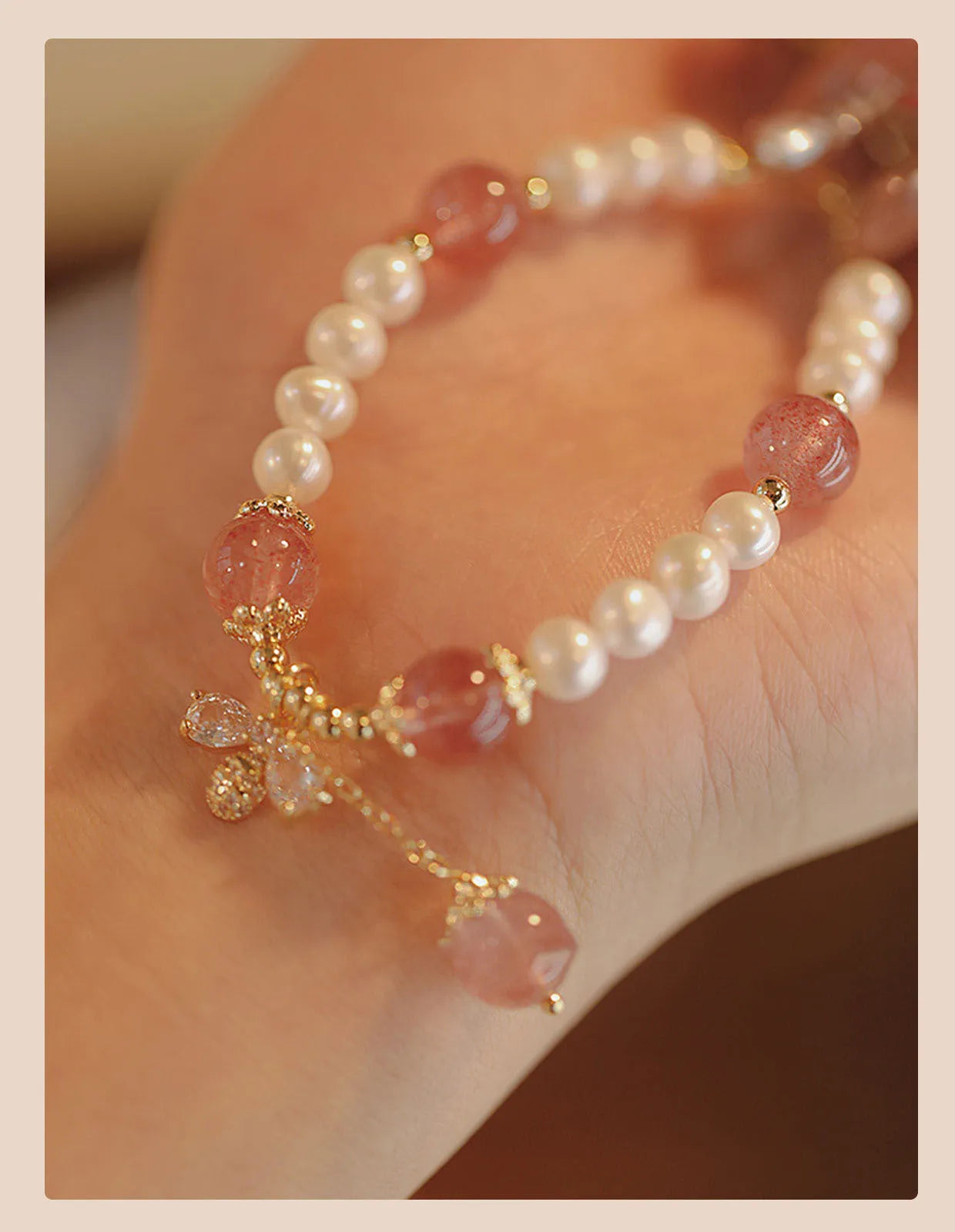 Women's strawberry quartz crystal bracelet with pearls and bow charm on wrist