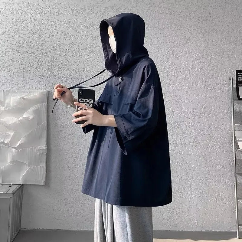A man wearing a loose-fit black hooded short sleeve t-shirt made of polyester for summer.