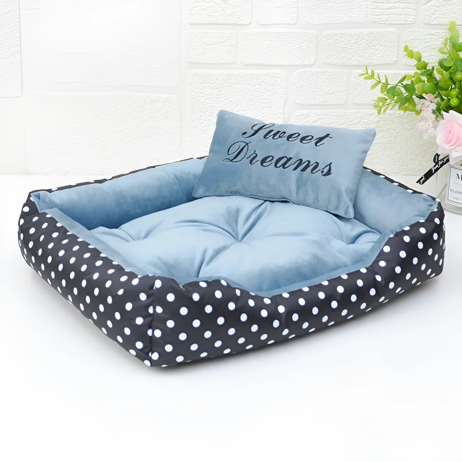 Polka dot print dog bed with matching embroidered cushion in grey, shown in a home setting.