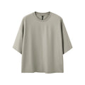 Man wearing a sand gray loose-fitting short sleeve pullover top.