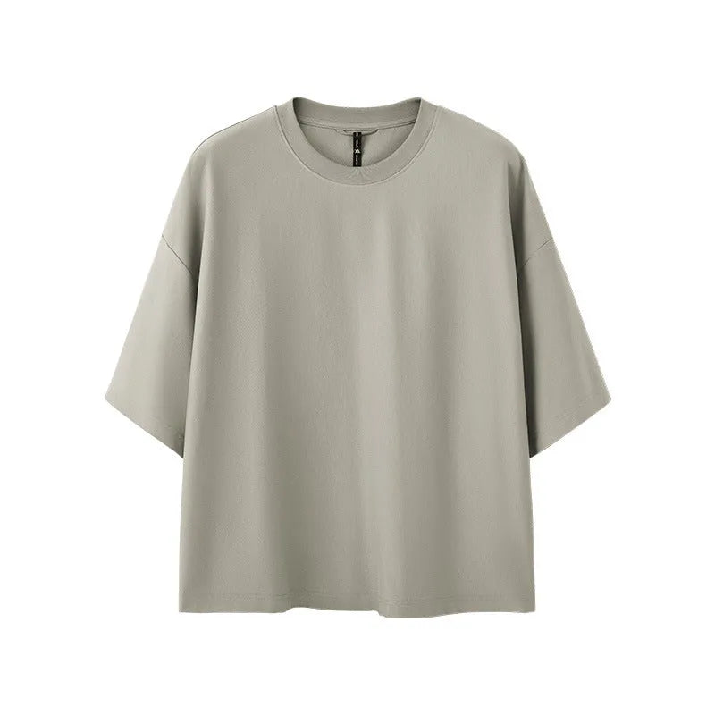 Man wearing a sand gray loose-fitting short sleeve pullover top.