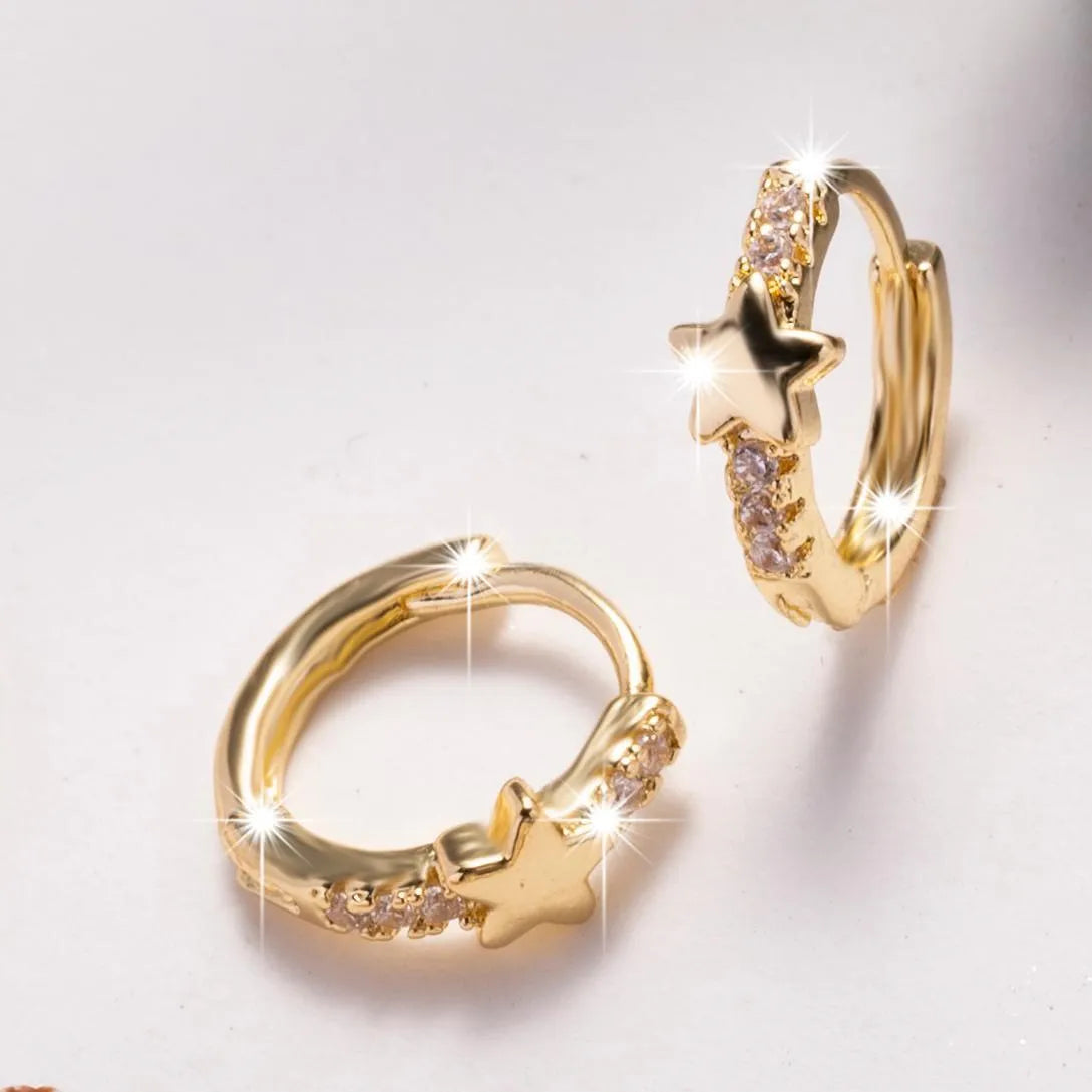 Gold copper five-pointed star earrings with inlaid zircon stones on a neutral background
