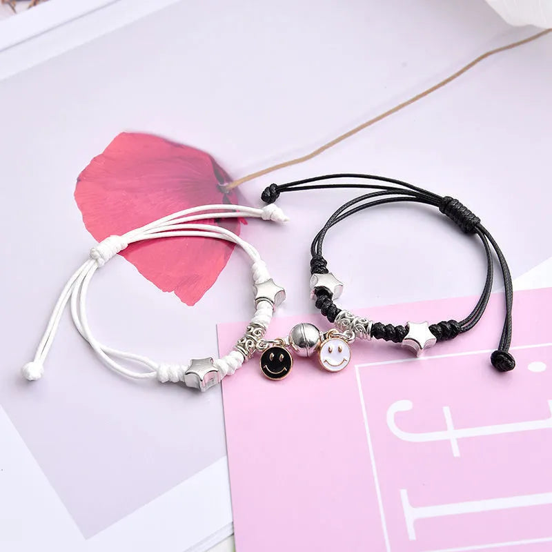 Pair of magnetic suction bracelets with alloy charms in various love and friendship themed designs on a wrist.