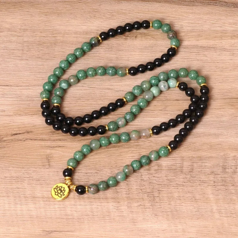 Green and black elastic beaded long bracelet with alloy components stretched on wrist