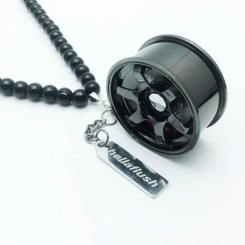 Stainless steel car tyre ornament with crystal glass bead chain hanging from a rearview mirror