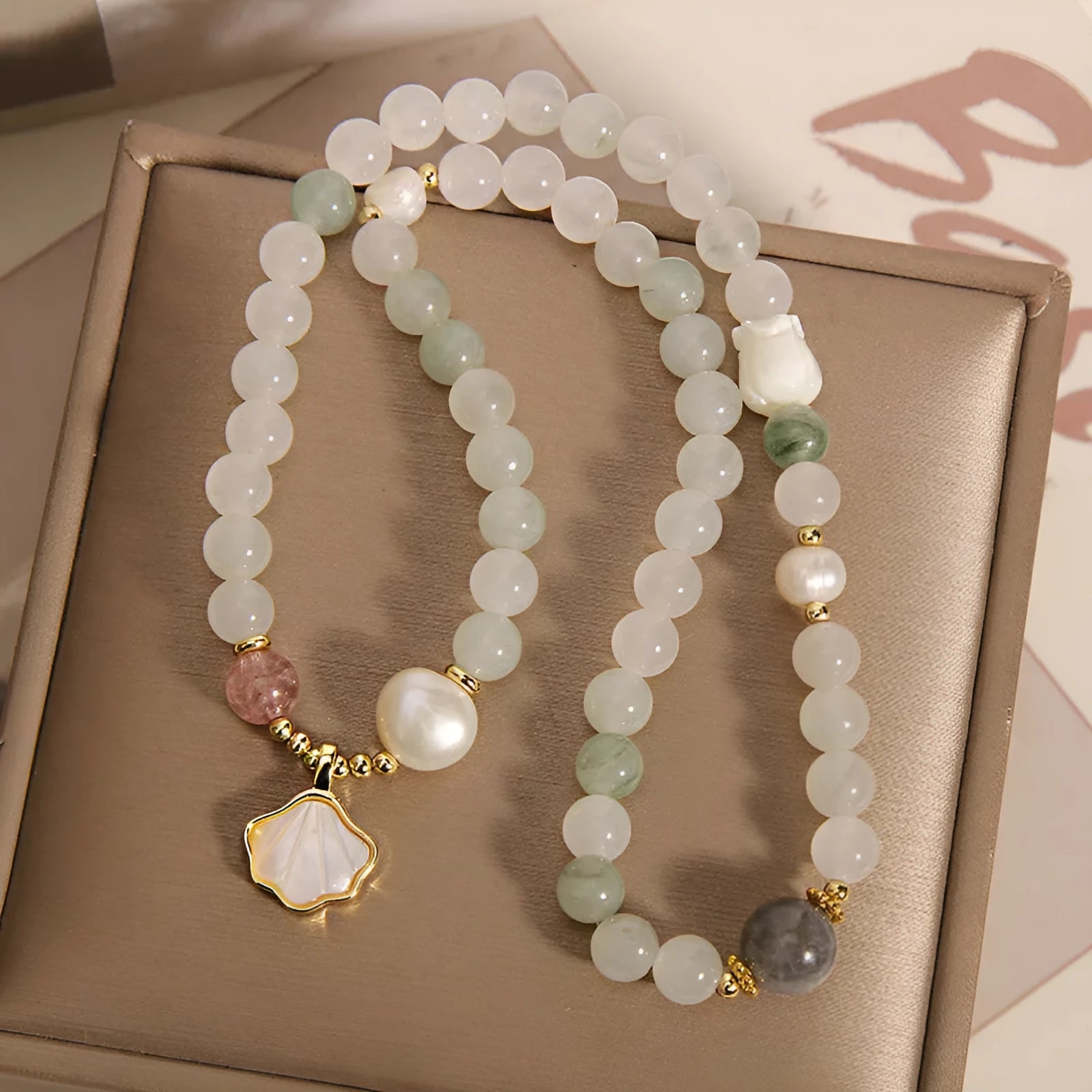Women's artistic crystal bracelet with a green Tianshan Jade ginkgo leaf pendant and gold-plated accents.