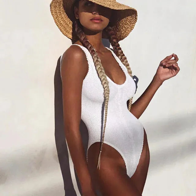 A woman's solid colour one-piece swimsuit with a backless design made from textured seersucker fabric.