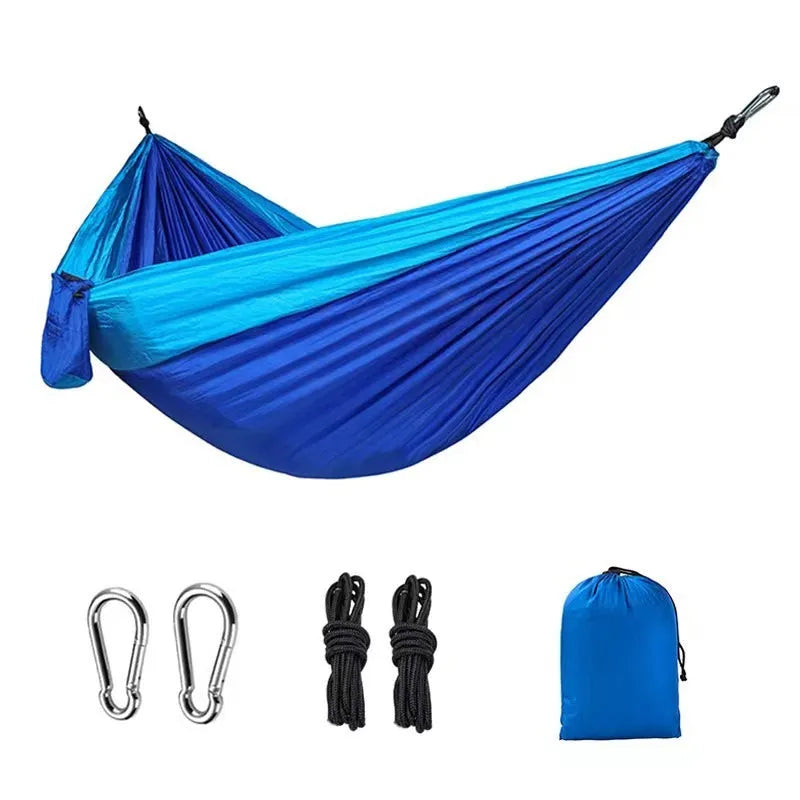 Blue ripstop nylon outdoor hammock with suspension ropes hung between trees