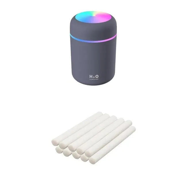 Pink USB desktop humidifier with LED lights and water tank on a wooden desk.