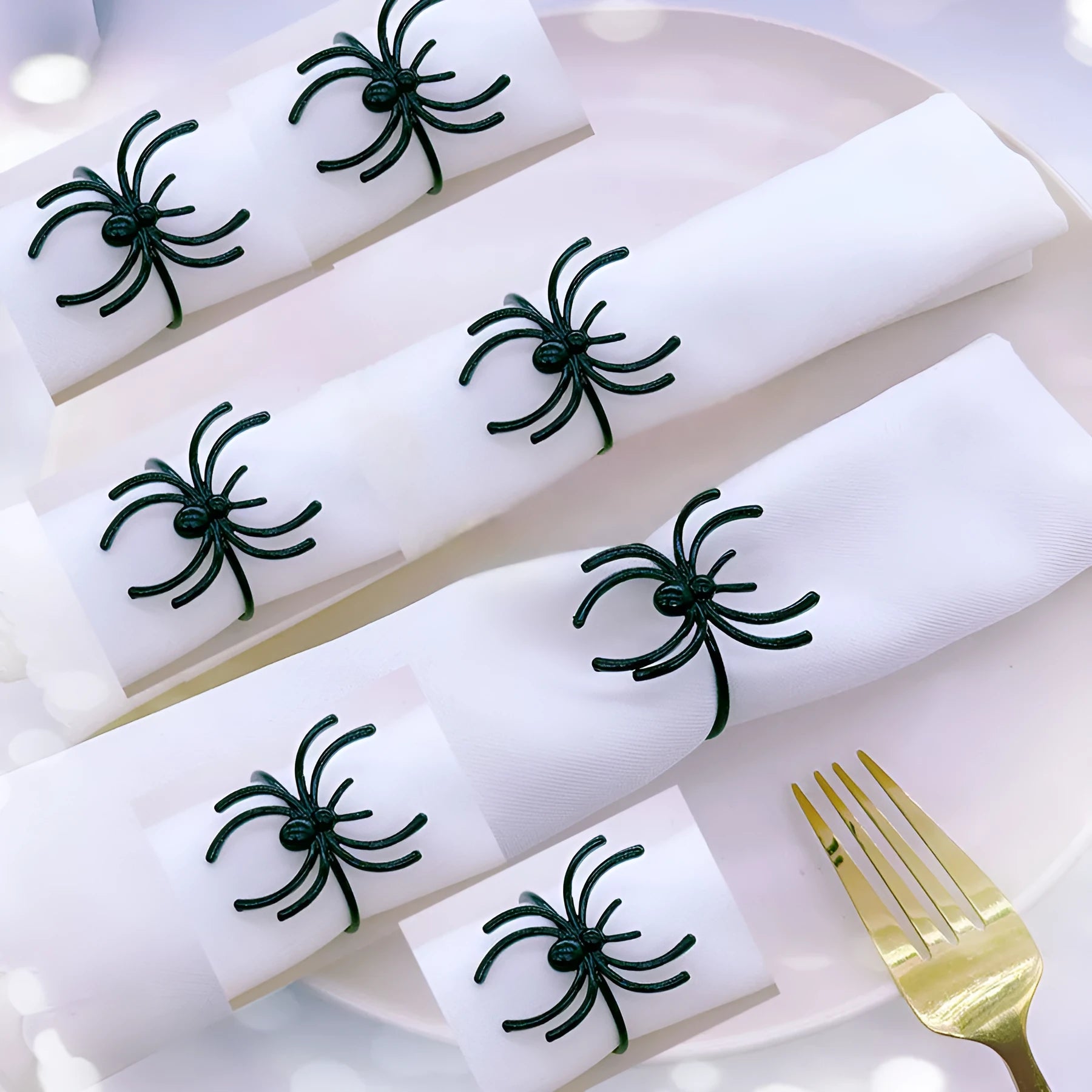 Six black metal spider-shaped napkin rings for Halloween table decoration.