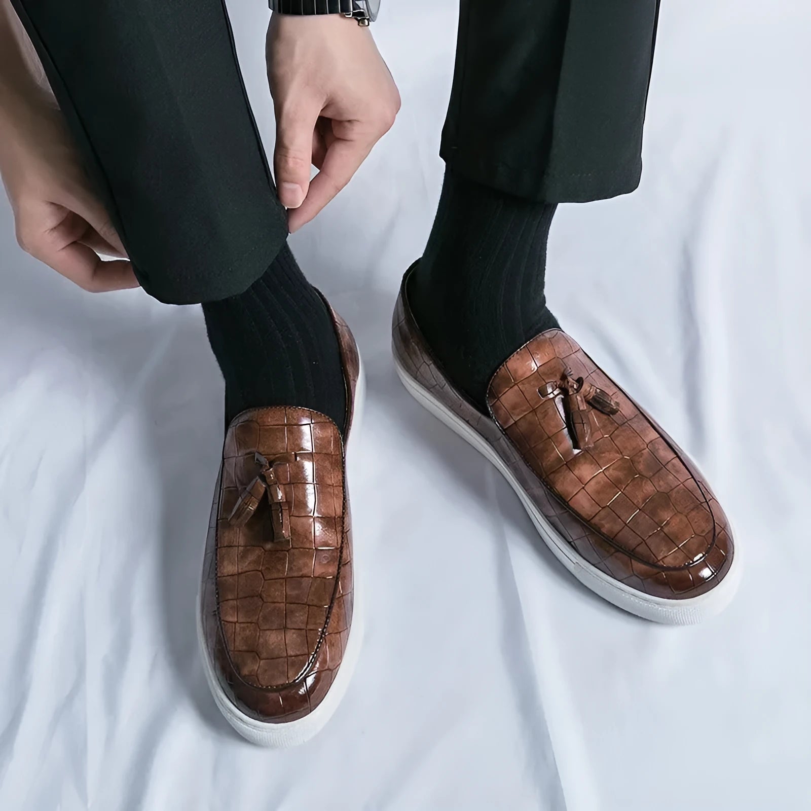 Men's black tassel slip-on sneakers with a round toe and rubber sole on a white background.