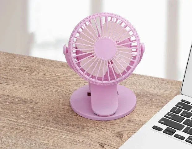 White USB rechargeable mini clip fan attached to a desk edge showing piano button switch and plastic blades.