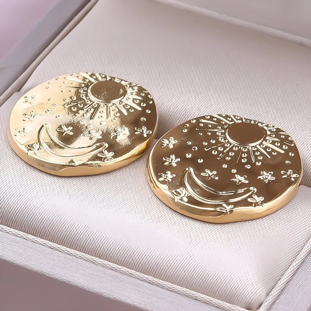 A pair of stainless steel geometric shell stud earrings in a gold electroplated finish on a white background.