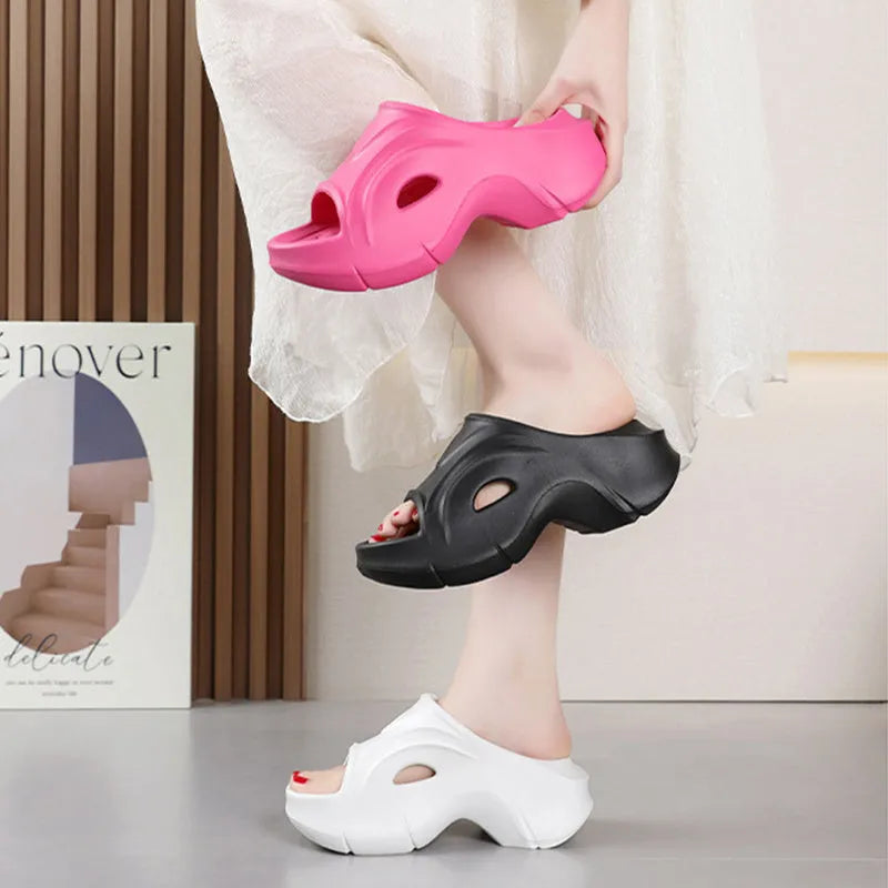 Women's thick-soled EVA slippers in rose red colour on a sandy beach.