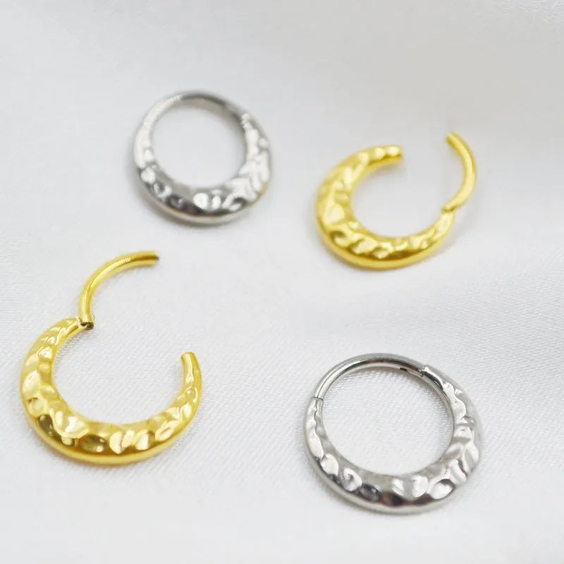 Close-up of a titanium concave-convex nose ring in gold finish, showing its textured profile and 1.2mm thickness.