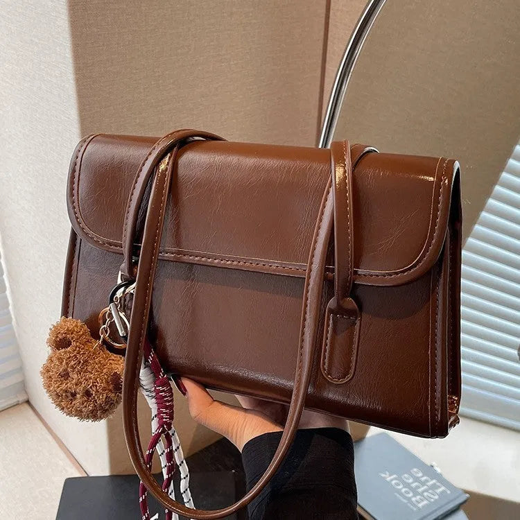 Brown women's Maillard-style PU leather shoulder bag with a double strap and a removable pendant accessory.