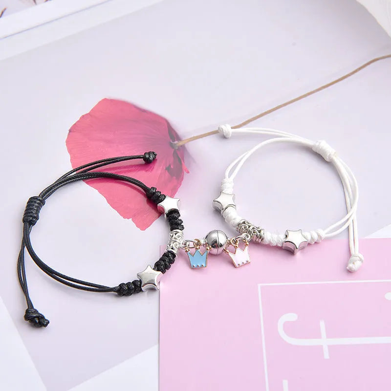 Pair of magnetic suction bracelets with alloy charms in various love and friendship themed designs on a wrist.