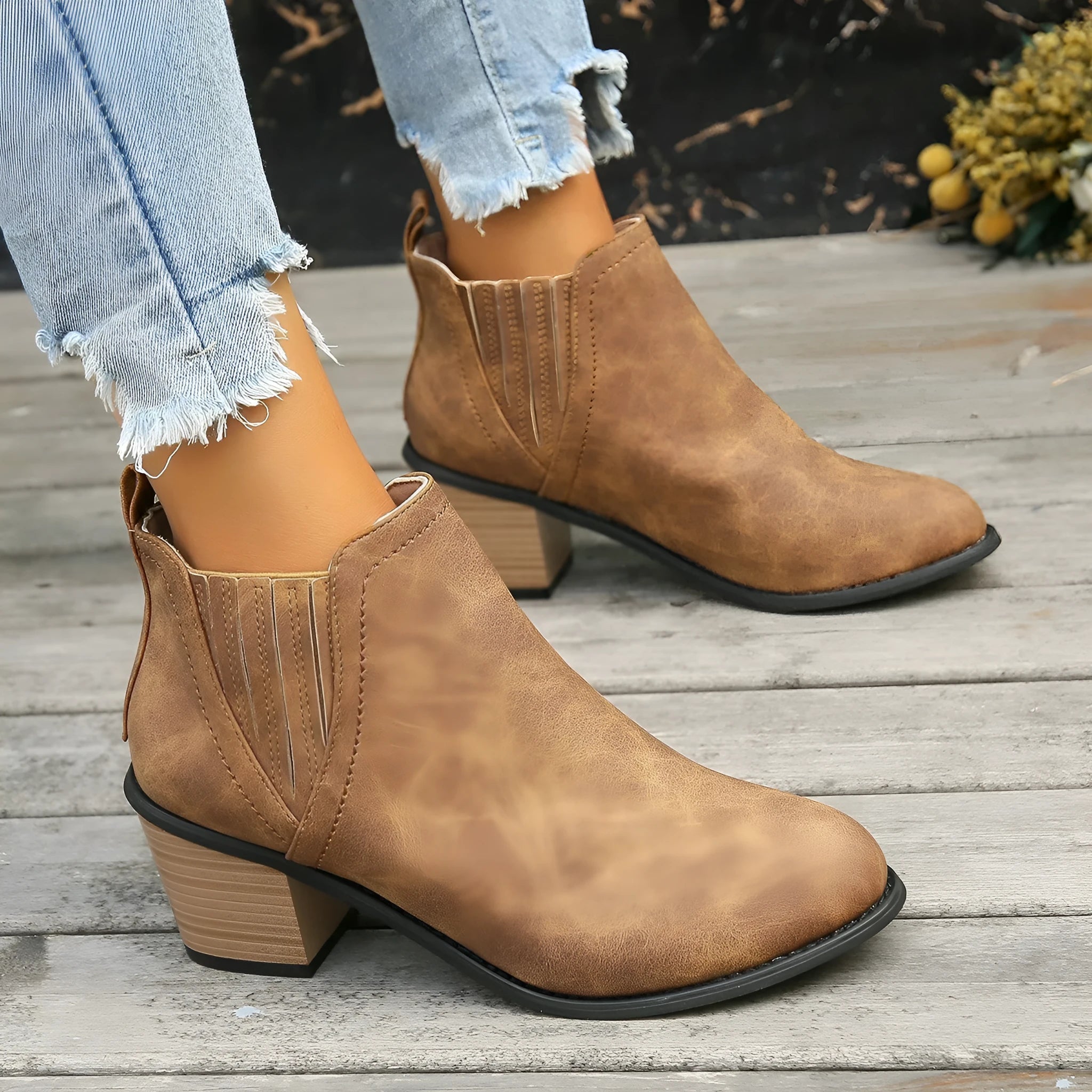 Women's black ankle boots with pointed toe and thick square heel on wooden floor