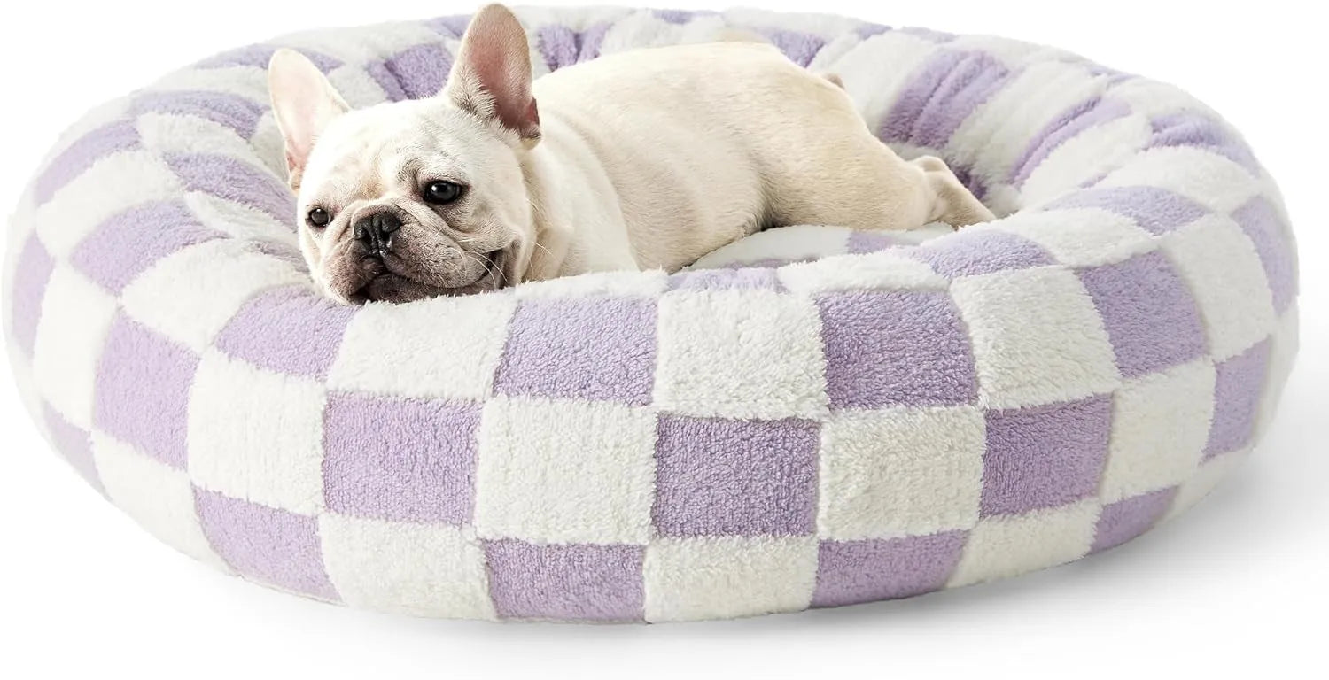 Round plastic dog bed with a blue and white plaid fabric cover, shown on a wooden floor.