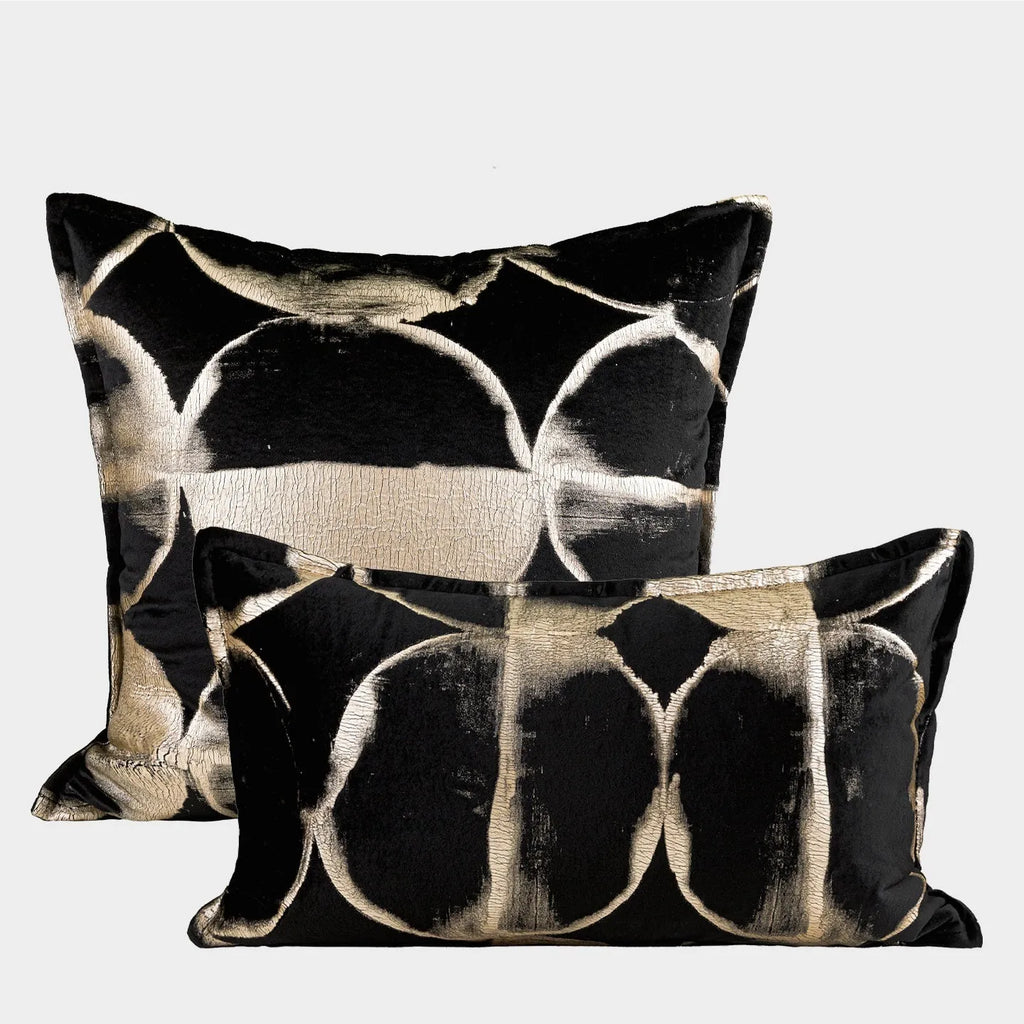 Black and gold abstract pattern decorative velvet cushion on a grey sofa.