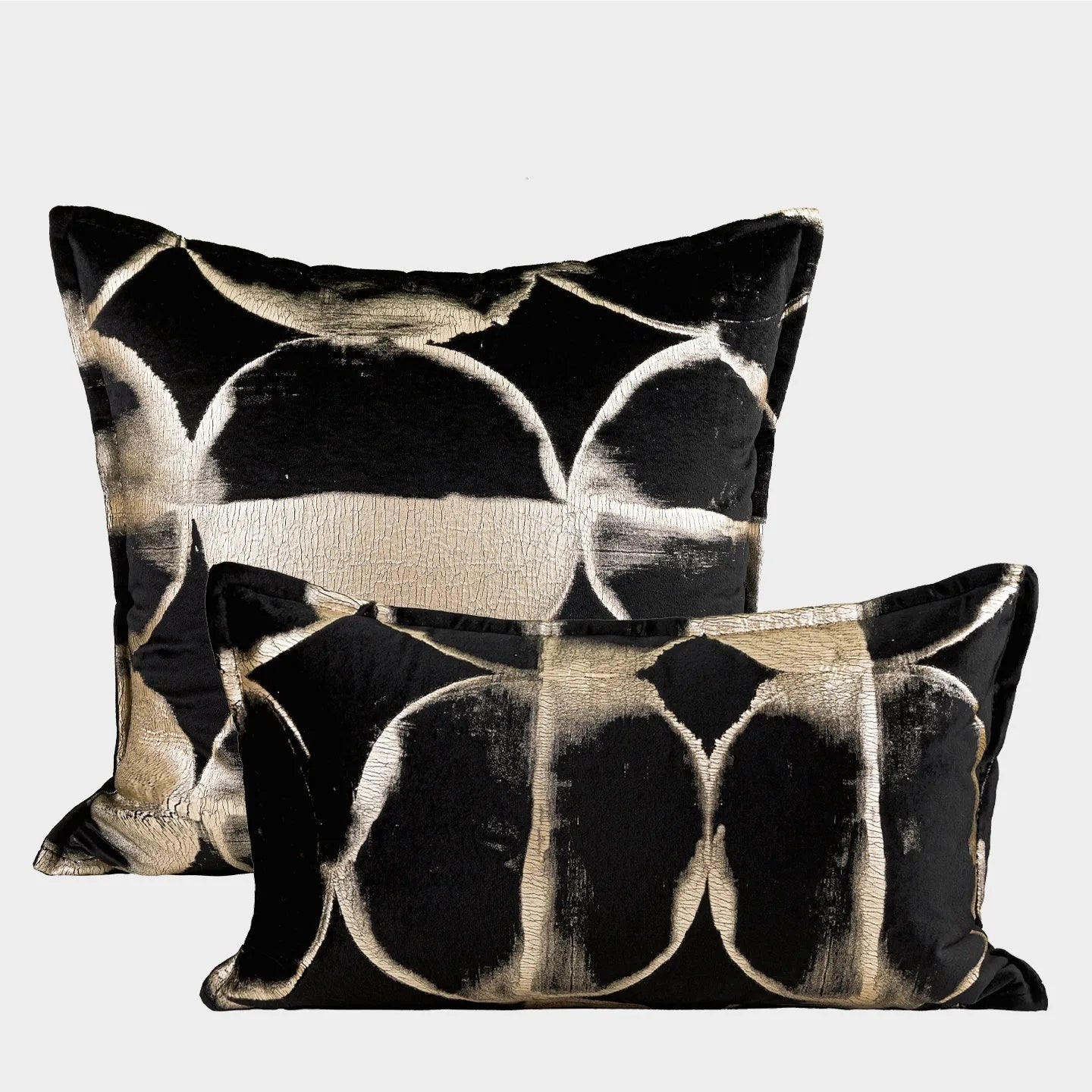 Black and gold abstract pattern decorative velvet cushion on a grey sofa.
