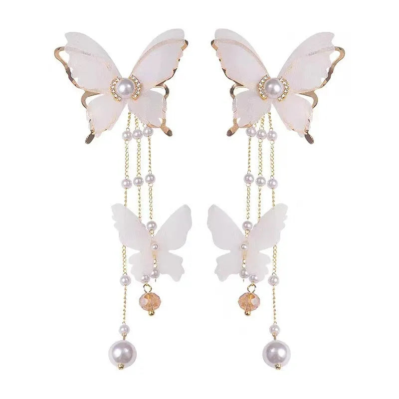 White butterfly-shaped drop earrings with pearl and rhinestone accents on a tassel lace design.