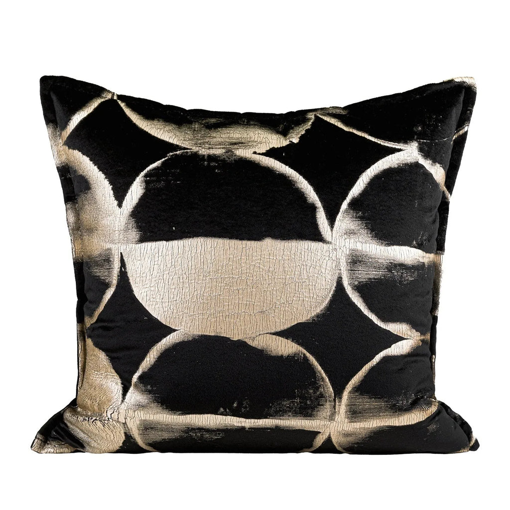Black and gold abstract pattern decorative velvet cushion on a grey sofa.