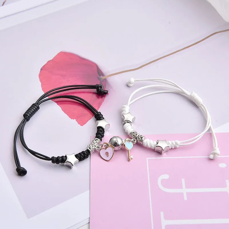 Pair of magnetic suction bracelets with alloy charms in various love and friendship themed designs on a wrist.