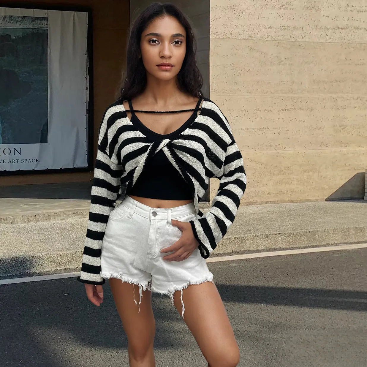 Woman wearing a striped long-sleeved cropped sweater in mercerised cotton, showcasing front and back wearable design.