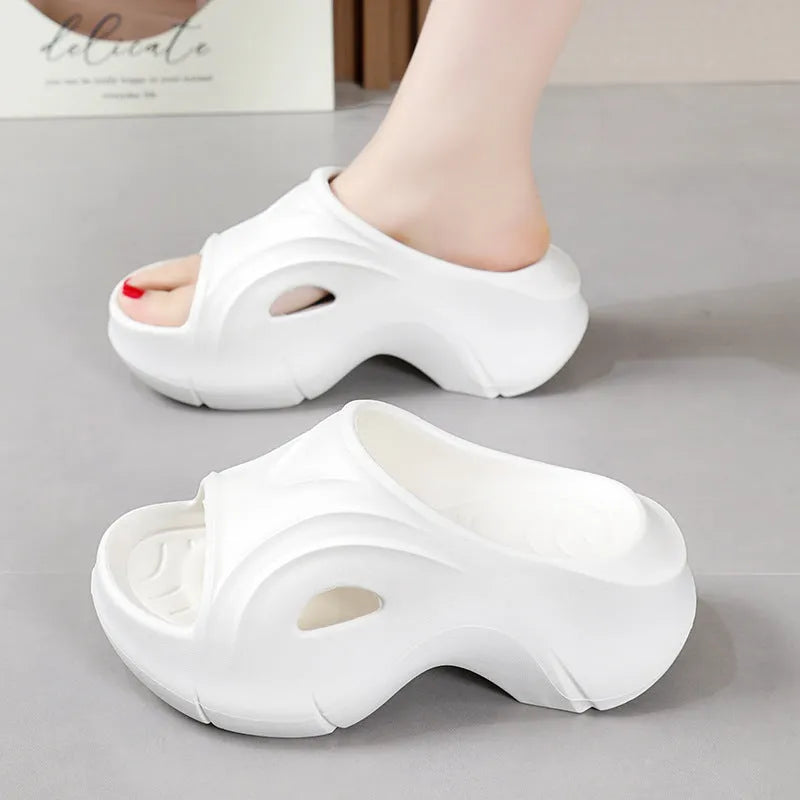 Women's thick-soled EVA slippers in rose red colour on a sandy beach.