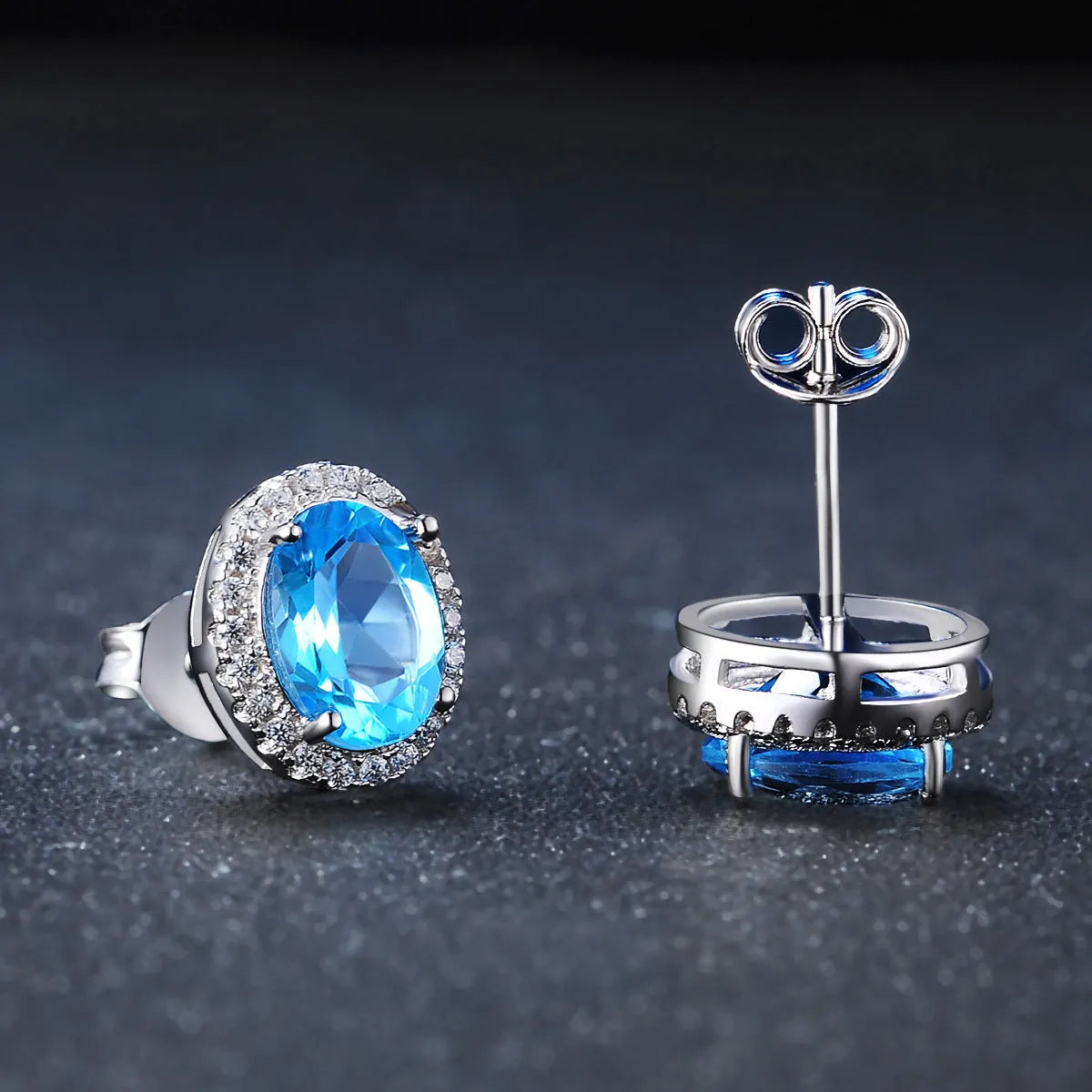 Four-piece 925 sterling silver jewellery set with blue topaz gemstones in a geometric design, showing earrings, ring, pendant and necklace.