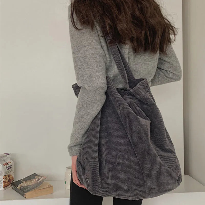 Large corduroy tote bag with soft handle, pleated detailing, and interior zipper pocket. Colour: black.