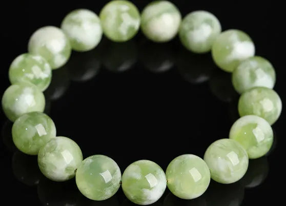 Green milk-in-water Xiuyan jade polished bracelet with geometric beads on a neutral background