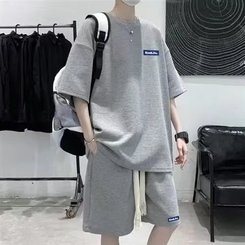Man wearing a grey waffle-textured short sleeve top and matching shorts leisure set.