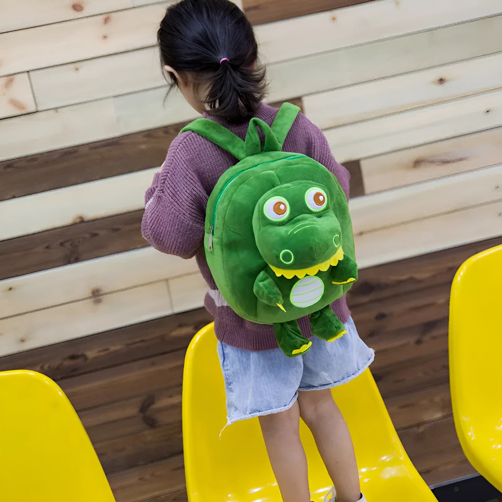 Soft blue plush dinosaur backpack for children with embroidery details and a single handle.