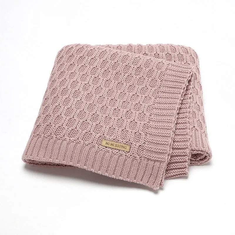 Solid colour infant blanket with textured lines, shown in a choice of colours including pink and beige.
