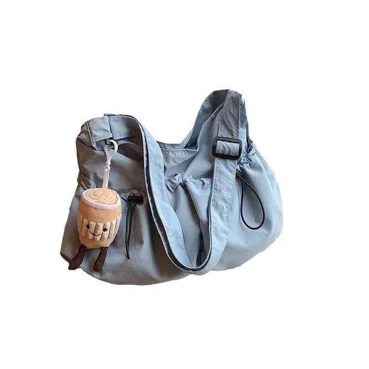 Green pleated crossbody student bag showing foldable polyester construction and internal mobile phone pocket