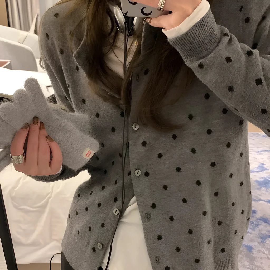 Women's grey dot pattern knitted cardigan with crochet flower details on sleeve.
