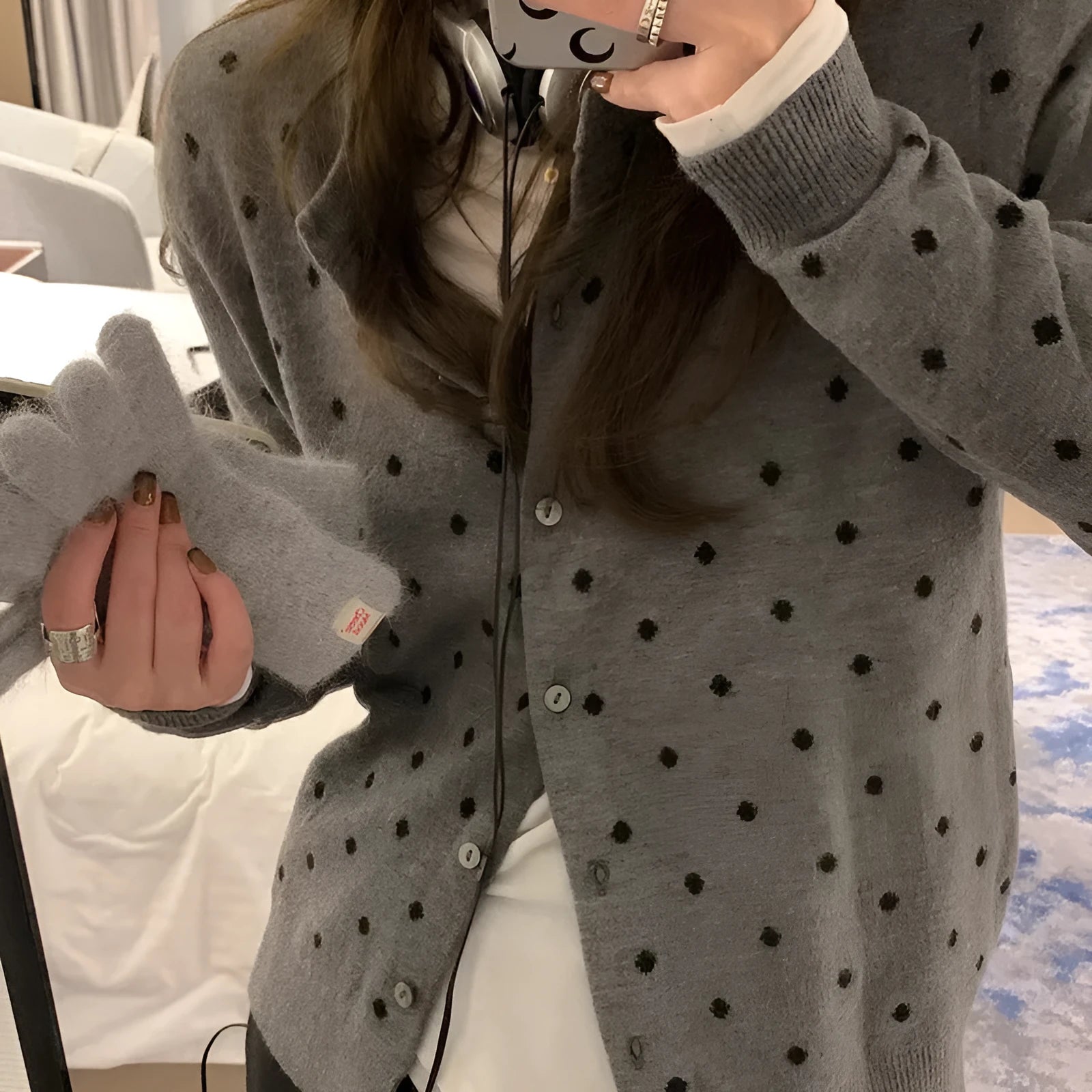 Women's grey dot pattern knitted cardigan with crochet flower details on sleeve.