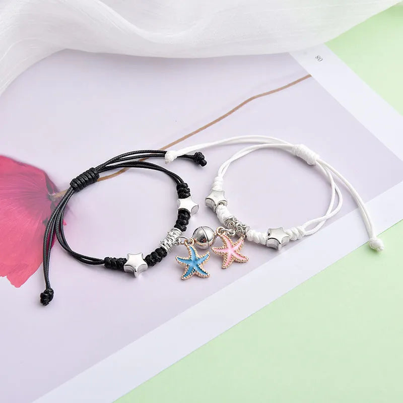 Pair of magnetic suction bracelets with alloy charms in various love and friendship themed designs on a wrist.